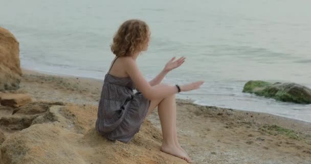 Mujer en vestido relajante sentado en una playa de mar — Vídeos de Stock