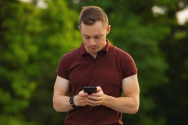 Parkta cep telefonu kullanan adam.