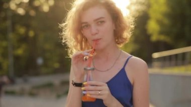 Parkta meyve suyu içen genç bir kadın