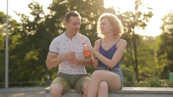 Lindos amantes bebiendo jugo en el parque — Vídeos de Stock