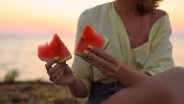 Mujer irreconocible comiendo sandía sentada cerca del mar — Vídeos de Stock