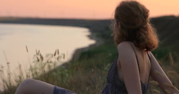 Vrouw ontspannen kijkend naar zee zonsondergang — Stockvideo