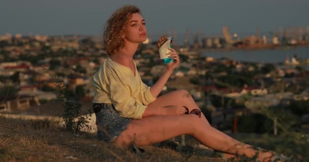 Кудрявая женщина ест шоколад над городом — стоковое видео