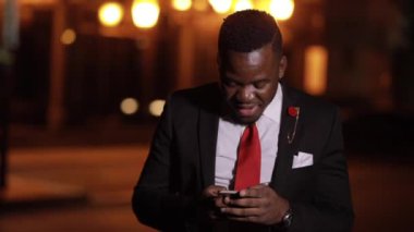 Afrikalı adam gece yarısı akıllı telefon kullanıyor.