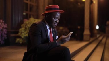 Afrikalı adam gece yarısı akıllı telefon kullanıyor.
