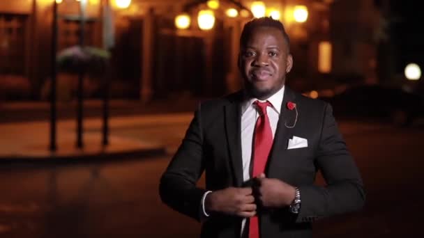 Африканский бизнесмен смотрит на камеру в ночном городе со скрещенными руками — стоковое видео