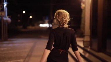Güzel, seksi bir kadın, gece caddesinde yürüyor.
