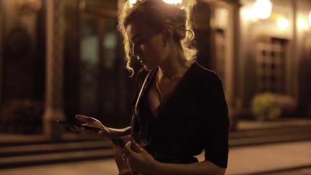 Žena odpovídá na příchozí hovor v nočním městě — Stock video