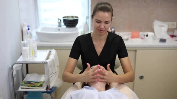 Косметолог делает массаж лица в салоне красоты — стоковое видео