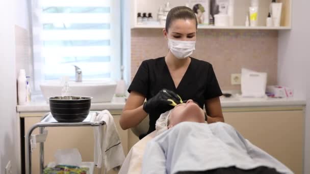 Cosmetology procedure, master wash off the mask with a sponge — Stock Video
