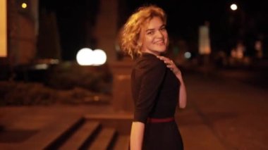 Güzel, seksi bir kadın, gece caddesinde yürüyor.