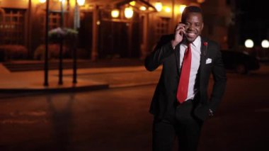 Afrikalı erkekler arkadaşlarını akıllı telefondan arar ve gece şehirde konuşurlar.