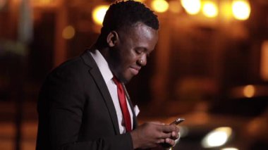 Afrikalı adam gece yarısı akıllı telefon kullanıyor.