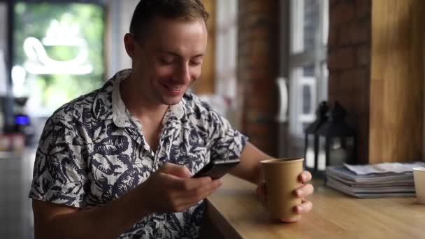 Muž používající telefon se směje v kavárně — Stock video