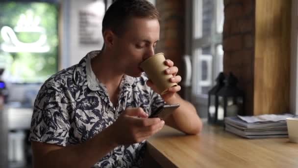 Muž pije kávu v kavárně pomocí telefonu — Stock video