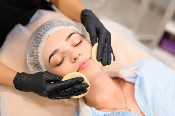 Cosmetology procedure in a beauty salon, wash off the face mask with a sponge