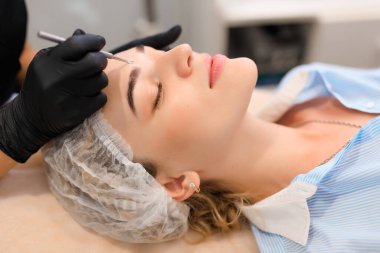 Güzellik uzmanı, güzellik salonunda sivilce temizleme kaşığı kullanarak müşterileri yüz yüze getiriyor.