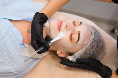 Güzellik salonunda kozmetoloji prosedürü, yüz maskesini fırçayla uygula