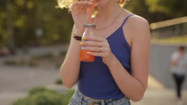 Parkta meyve suyu içen genç bir kadın
