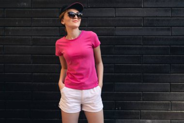 Tuğla duvarda duran pembe tişörtlü güzel kadın.