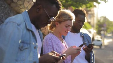 Şehirdeki akıllı telefonlarına bakan çok ırklı arkadaşlar.