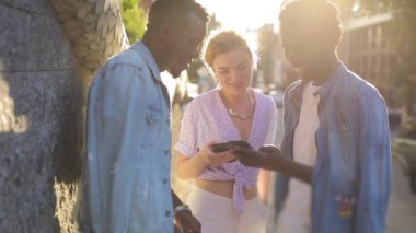 Akıllı telefonlarında fotoğraflara bakan çok ırklı arkadaşlar.