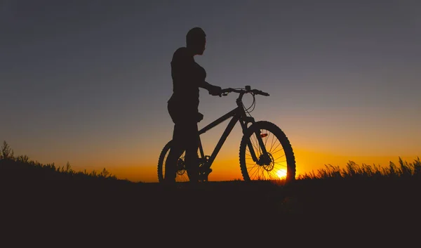 Silueta de hombre de pie con bicicleta de montaña al atardecer — Foto de Stock