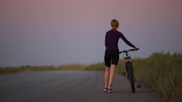 若い女性は自転車を道路の上で転がして — ストック動画