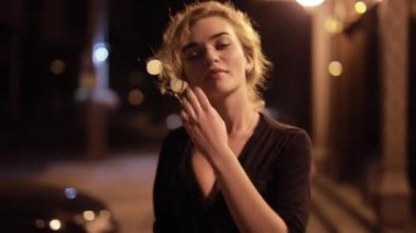 Güzel, seksi bir kadın, gece caddesinde yürüyor.