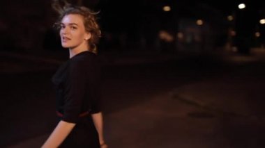 Güzel, seksi bir kadın, gece caddesinde yürüyor.