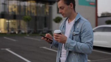 Adam şehirde akıllı telefonla yürüyor.