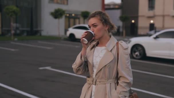 Vrouw in trench jas loopt te drinken afhaalkoffie — Stockvideo