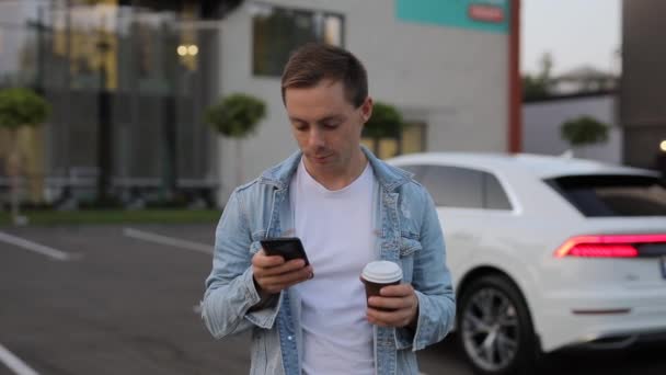 Чоловік п'є каву в місті за допомогою смартфона — стокове відео