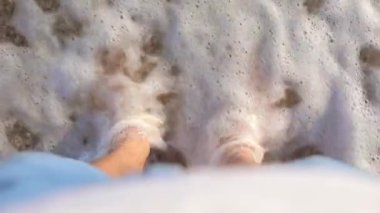 Okyanus dalgaları deniz kıyısında duran erkek bacakları kapladı.