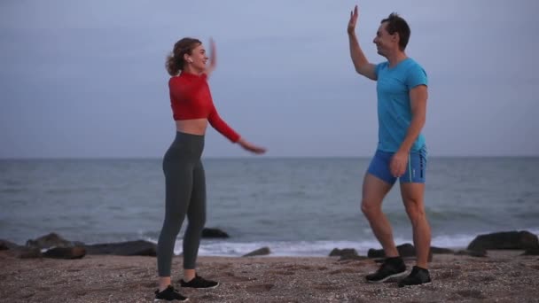 Felices abrazos de pareja deportiva en la playa del océano en cámara lenta — Vídeos de Stock