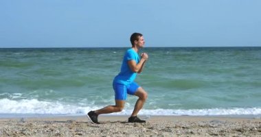 Okyanus sahilinde hamleler yapan genç bir adam.