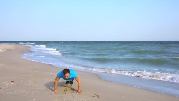 Mladý muž dělá burpees cvičení na pláži oceánu ve zpomalení — Stock video