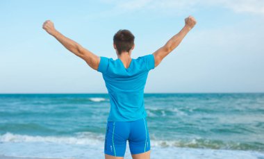 Kaldırılmış elleriyle mutlu özgürlük adamı Denize, geriye doğru bakıyor