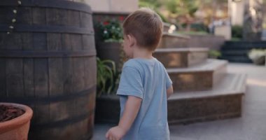 Curious and shy boy knocks on wine barrel