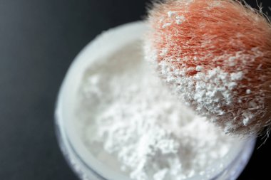 Siyah arka plan üzerinde şeffaf gevşek toz ve makyaj fırçası