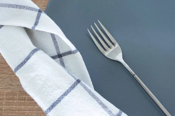 Silver fork, empty plate and napkin on table