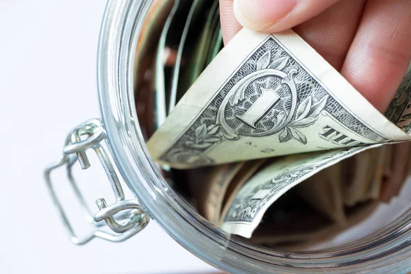 Hand pulls one dollar banknote in glass jar — Stock Photo, Image