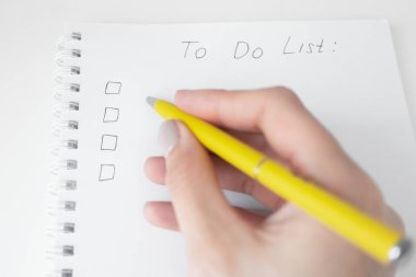 Boş kontrol listesi ve sarı kalemile kadın el ile yapılacaklar listesi. 