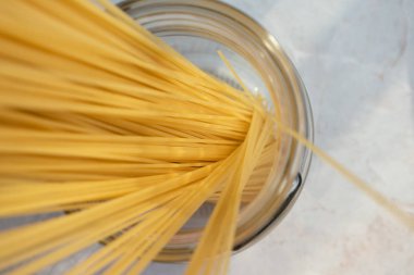 Cam kavanozda kuru klasik spagetti. İtalyan makarnası için malzeme, en iyi manzara. Seçici odaklı çiğ gıda, yakın çekim