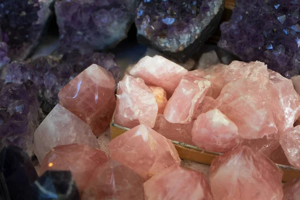Close-up of natural rose quartz surrounded by purple minerals