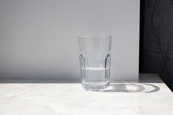 Beyaz duvara karşı granit bir masada saf su bardağı