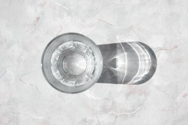 Vaso de agua clara sobre una mesa de granito blanco a la luz del día, superior v —  Fotos de Stock