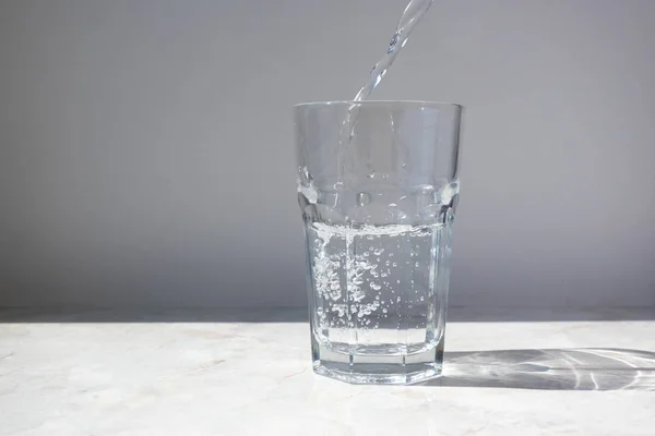 Klares Wasser in Glas auf weißem Wandhintergrund — Stockfoto