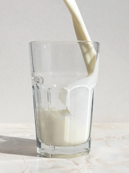 Açık mermer masada kalan bir bardağa dökülen taze süt — Stok fotoğraf