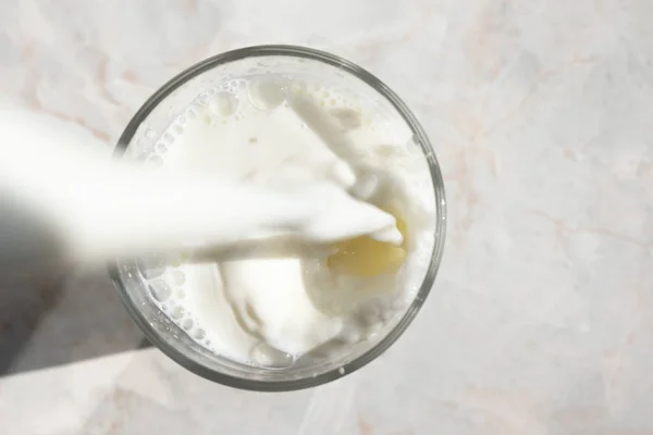 Primer plano de la corriente de leche fresca vertiendo en un vaso con salpicadura de un —  Fotos de Stock